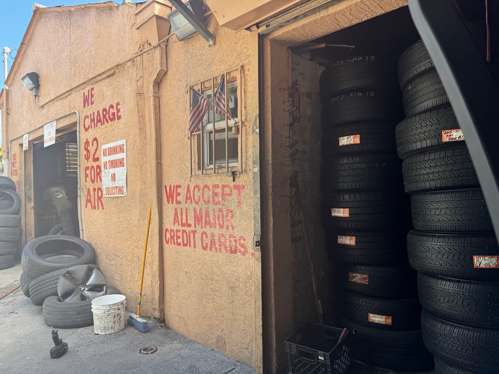 George's Tires shop entrance in Miami, with stacked tires and hand-painted pricing signs